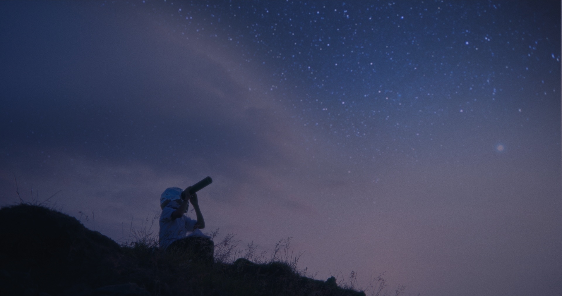Fotograma de Reaching the Stars: un niño observa el cielo con un telescopio