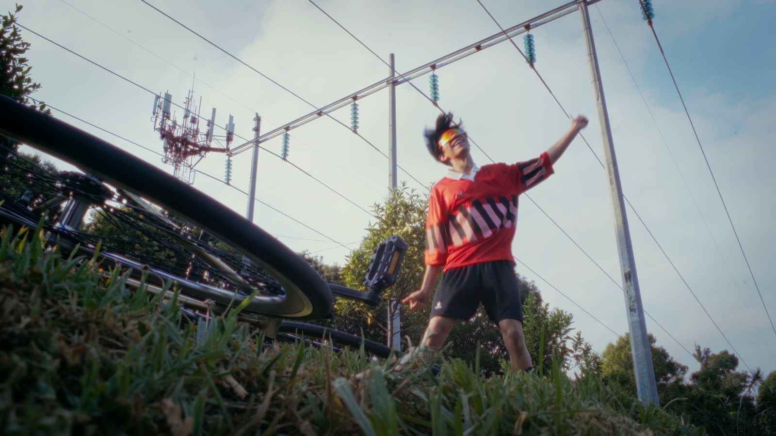 Fotograma de Niñazo: un joven celebra junto a una bicicleta bajo líneas eléctricas